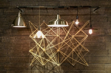 Modern light fixtures hanging in front of complex geometrical design. Abstract Interior design modern and minimal. Light bulbs displaying brightly.