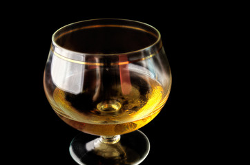 Shot glass with alcohol on a black background.