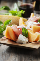 Antipasto with melon, mozzarella, ham and basil