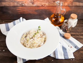 Risotto with mushrooms and chicken on a white plate on a wooden