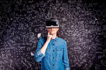 Beautiful woman wearing virtual reality goggles against big blac
