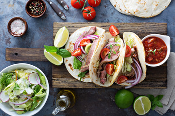 Steak tacos with sliced meet, salad and tomato salsa
