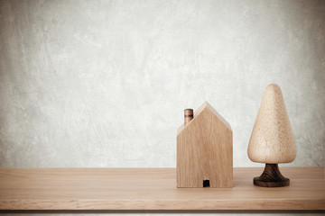 Wooden house and tree models on table over cement background