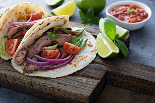 Steak tacos with sliced meet, salad and tomato salsa