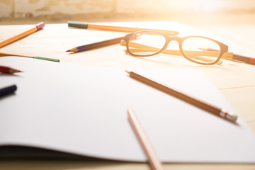 desk of student in school or home with drawing equipment color pencil and glasses in morning