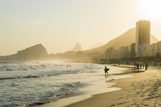 Golden sun setting behind a silhouette of the Rio de Janeiro skyline at the Leme end of Copacabana Beach