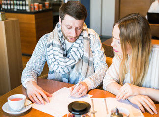 Fototapeta premium Male and female business colleagues working together on a hard problem at indoors cafe