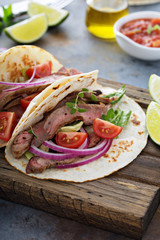 Steak tacos with sliced meet, salad and tomato salsa
