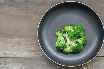 Broccoli in pan on the old wood table