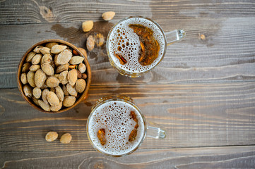 Two Oktoberfest beers with pistachio nuts on a wooden table, top view