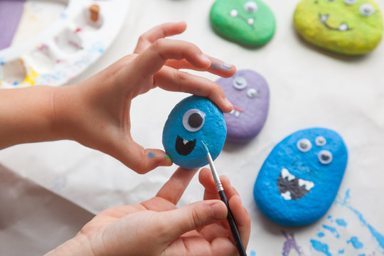 Child painting a stone for making a monster craft
