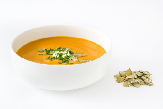 Pumpkin soup with cream and pumpkin seeds isolated on white background


