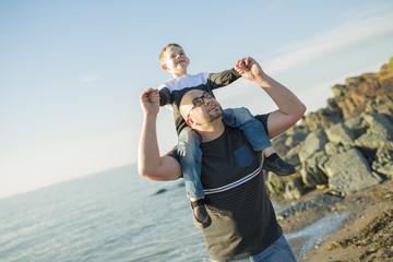 Son on father shoulders at the beach having fun  sunset together