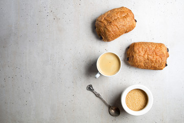 Czekoladowy croissant z kawą na szarym tle