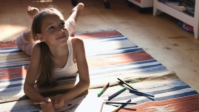 Pretty little girl drawing with color pencils on a floor in her nursery room