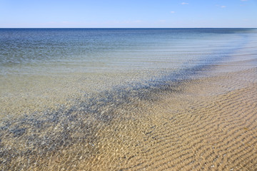 Calm sea surface near coastline. Seascape in sunny day under clear skies.
