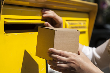 Frau versucht kleines Päckchen in Briefkasten zu werfen