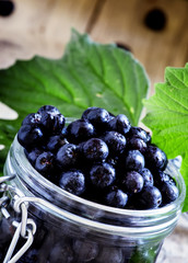 Fresh berries chokeberry in a glass jar, vintage wooden backgrou