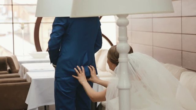 Funny moment of beautiful bride touching grooms butt and smiling