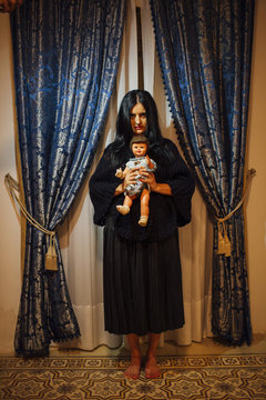 Black-haired woman with doll in hands