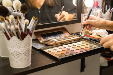 Makeup brushes and make-up in the shadow of the hands, in the beauty salon.