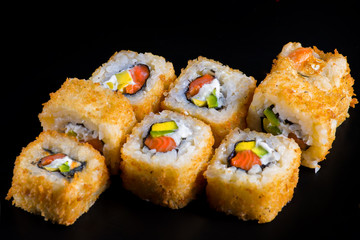Japanese rolls with fish on a black background