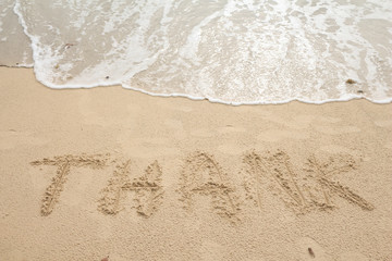 Write thank on the sand, beach background. 