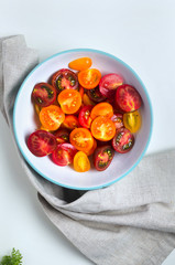 Multicolored tomatoes on a plate with basil leaves on top