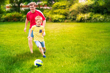 Happy family plays football in sunny park