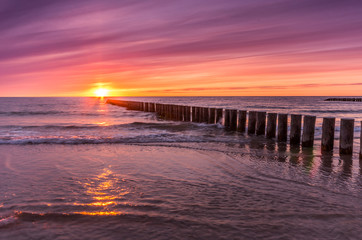Fototapeta na wymiar Baltic sea coast on colorful sunset with wooden groyne, Poland