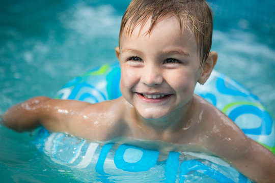 Little boy swimming in the pool rubber ring, having fun in aquapark.

