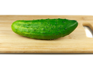 Green cucumber on wooden cutting board