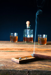 Cigar and whisky with ice on wooden table