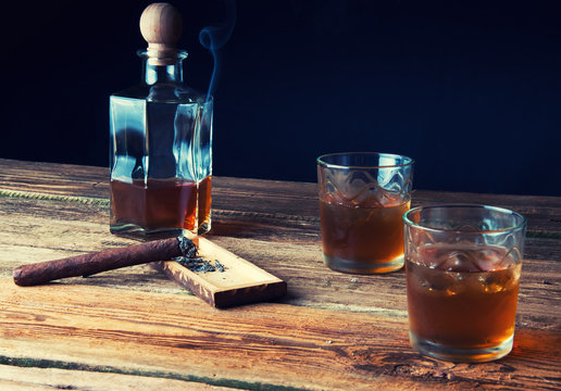 Whisky with ice and cigar on wooden table