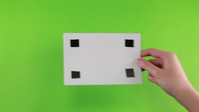 Hand of female put a white photo paper with black mark ( for tracking motion) on green screen background 