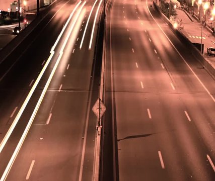 Timelapse of Traffic on a United States highway at night showing light streaks, sepia tone.
