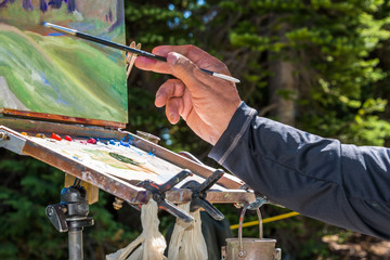 Artist's Hand with Paint Brush Painting with an Oil Palette a Mountain Wildflower Landscape on...