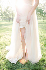 Fototapeta na wymiar Young beautiful bride in wedding dress in park over sunlightYoun