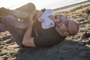Son on father shoulders at the beach having fun  sunset together
