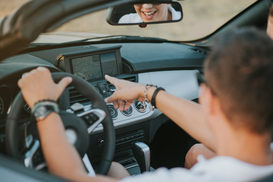 Cheerful Family Couple Lovers Smiling And Cheating To Each Other Driving A Cabriolet And Searching The Location They Need By Pointing On Car Gps System