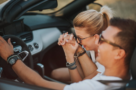 cheerful family couple lovers smiling and cheating to each other driving a cabriolet and searching the location they need by pointing on car gps system