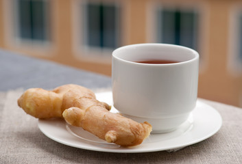 Чай в лаконичной чашке и корень имбиря на мешковине на...