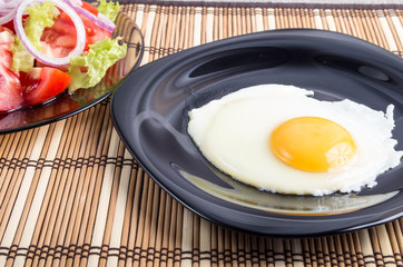 Closeup view on fried eggs with yolk on a black plate