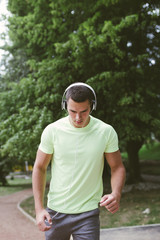 Naklejka na ściany i meble Young handsome man jogging in a park and listening to music.