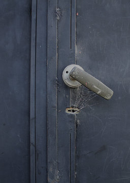 picaporte en puerta vieja de metal azul con tela de ara&ntilde;a