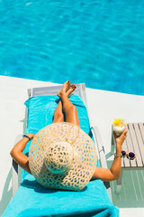 Woman at the poolside with pina colada cocktail