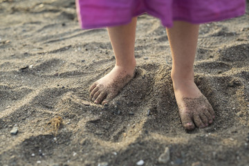 Baby feet walking on sand beach at sunset