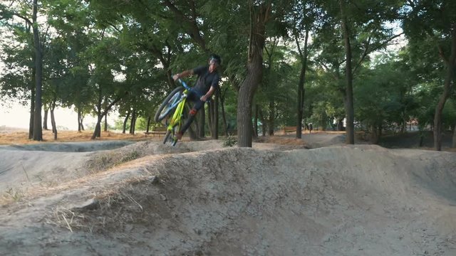 A mountain biker jumping on track at sunrise or sunset, slow motion, dolly