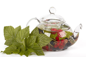Teapot with fruit tea and green leaves