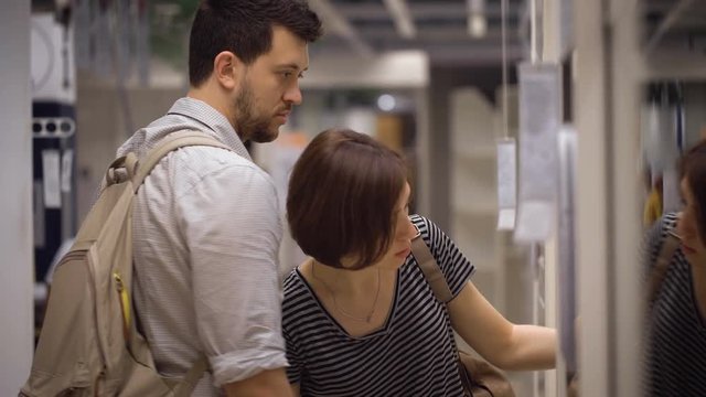 Beautiful young couple choosing boxes and containers in shop
